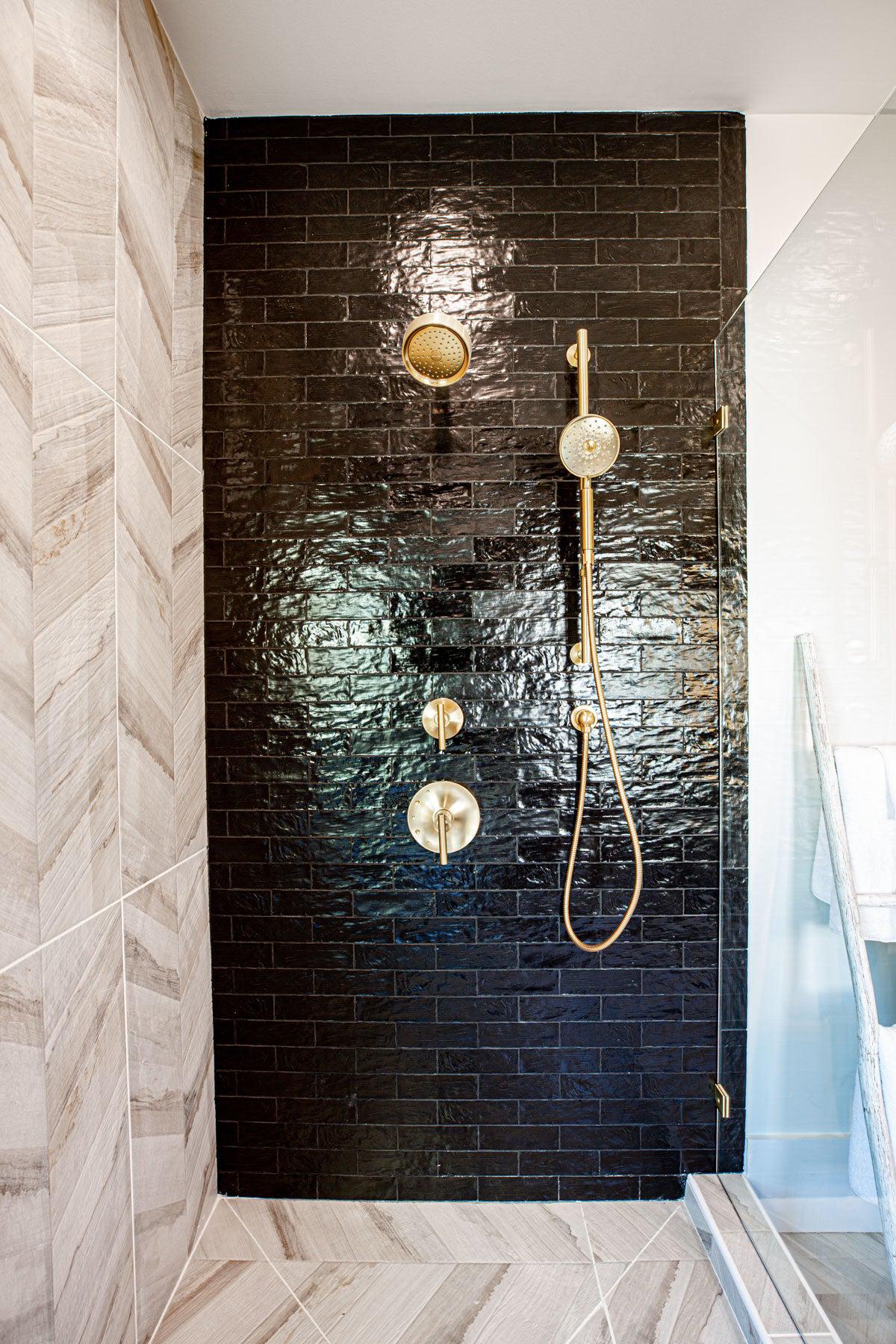 Glossy Black Ceramic Subway Tile Shower with Brass Fixtures and White Oak Chevron Porcelain Floor TIles
