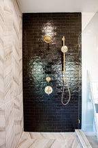 Glossy Black Ceramic Subway Tile Shower with Brass Fixtures and White Oak Chevron Porcelain Floor TIles