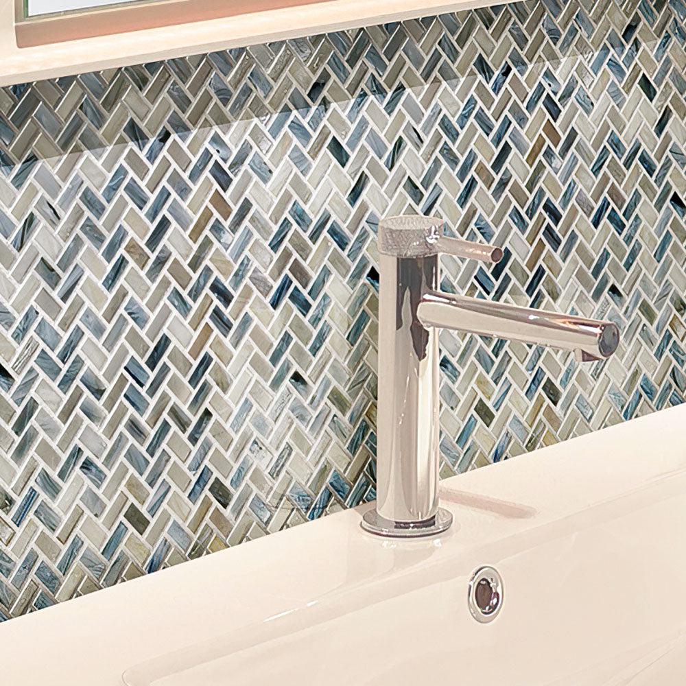 Silver faucet in the bathroom on the background of the Blue Grey Herringbone Mosaic wall