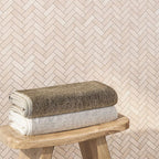 Wooden Bench with Towels on Background Crema Marfil Herringbone 1X3 Polished Marble Mosaic Wall