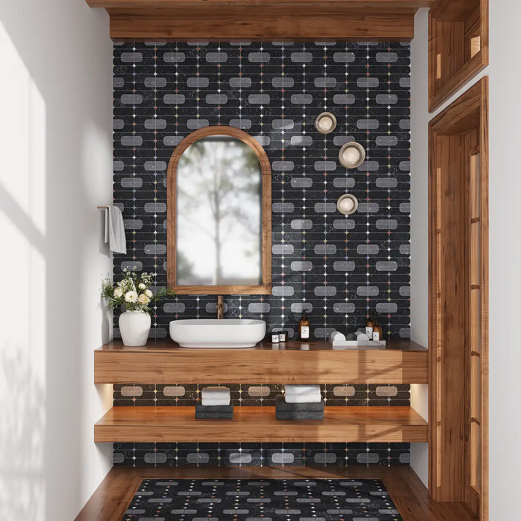 Bathroom with wooden vanity, sink, and decorative mirror against a patterned black wall tile with a matching bathroom floor inset into wood