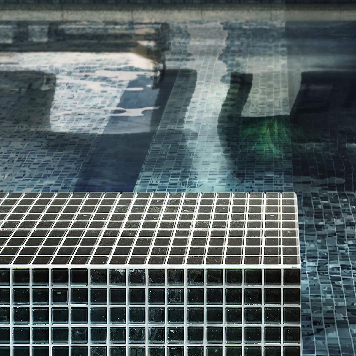 Black polished glass tile swimming pool edge in sunlight 