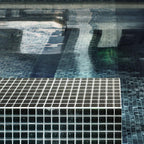 Black polished glass tile swimming pool edge in sunlight 