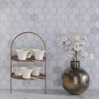 A Set of Tea Cups and a Brass Jug with Flowers against the Textured Carrara And Glass Hexagon Mosaic Wall