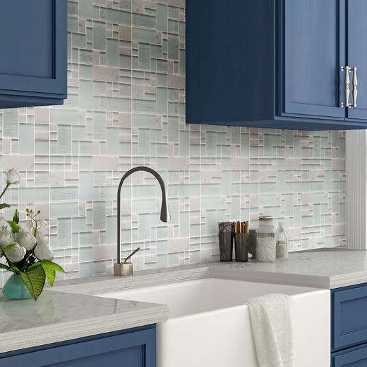 Geometric white glass backsplash with blue cabinets and a farm sink